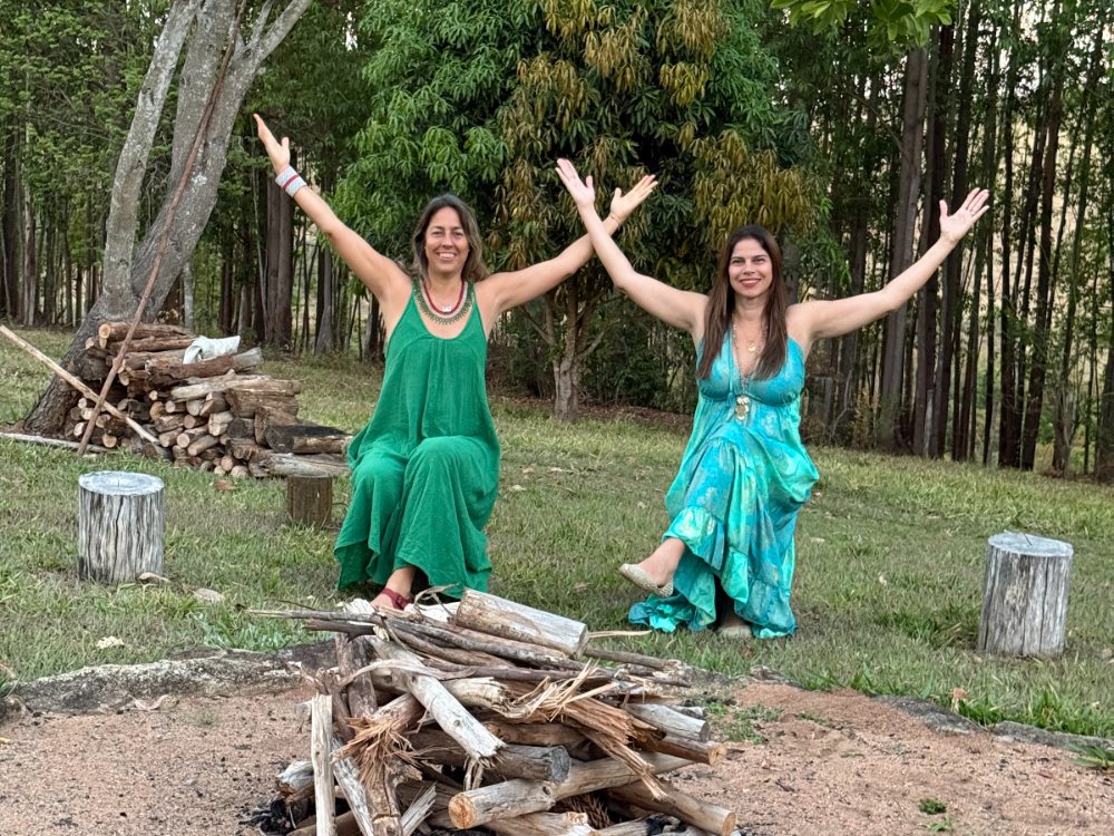 Aléxia e Lara de braços abertos junto à fogueira